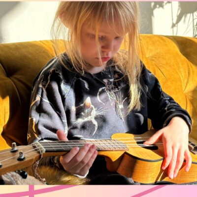 Image of a child playing a small guitar or a ukulele 