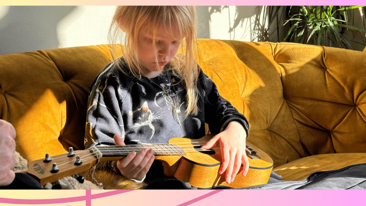 Image of a child playing a small guitar or a ukulele
